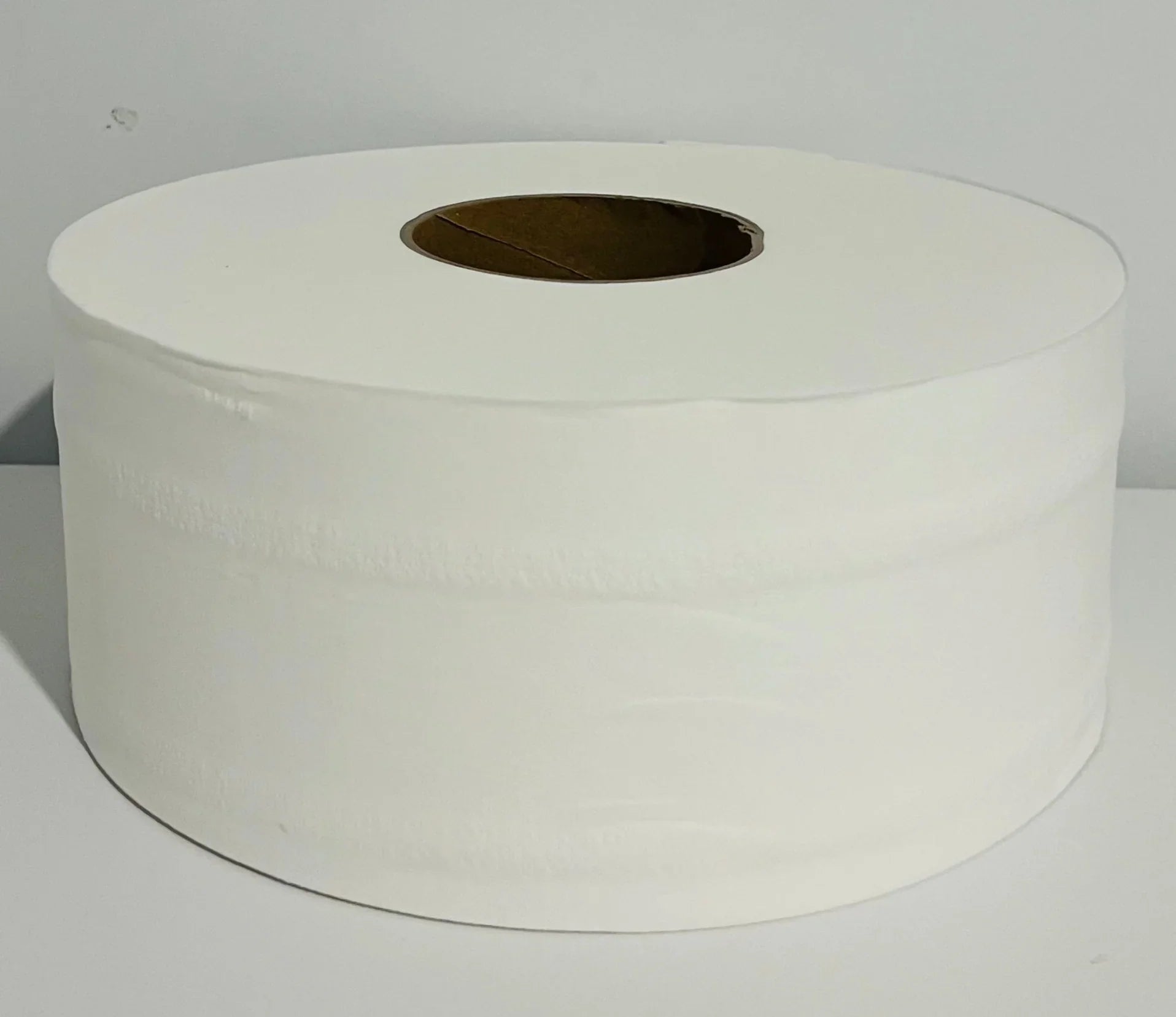 Large white jumbo toilet paper roll on plain background, commercial cleaning supply