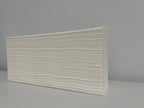 Stack of folded white paper hand towels on a plain surface for cleaning use
