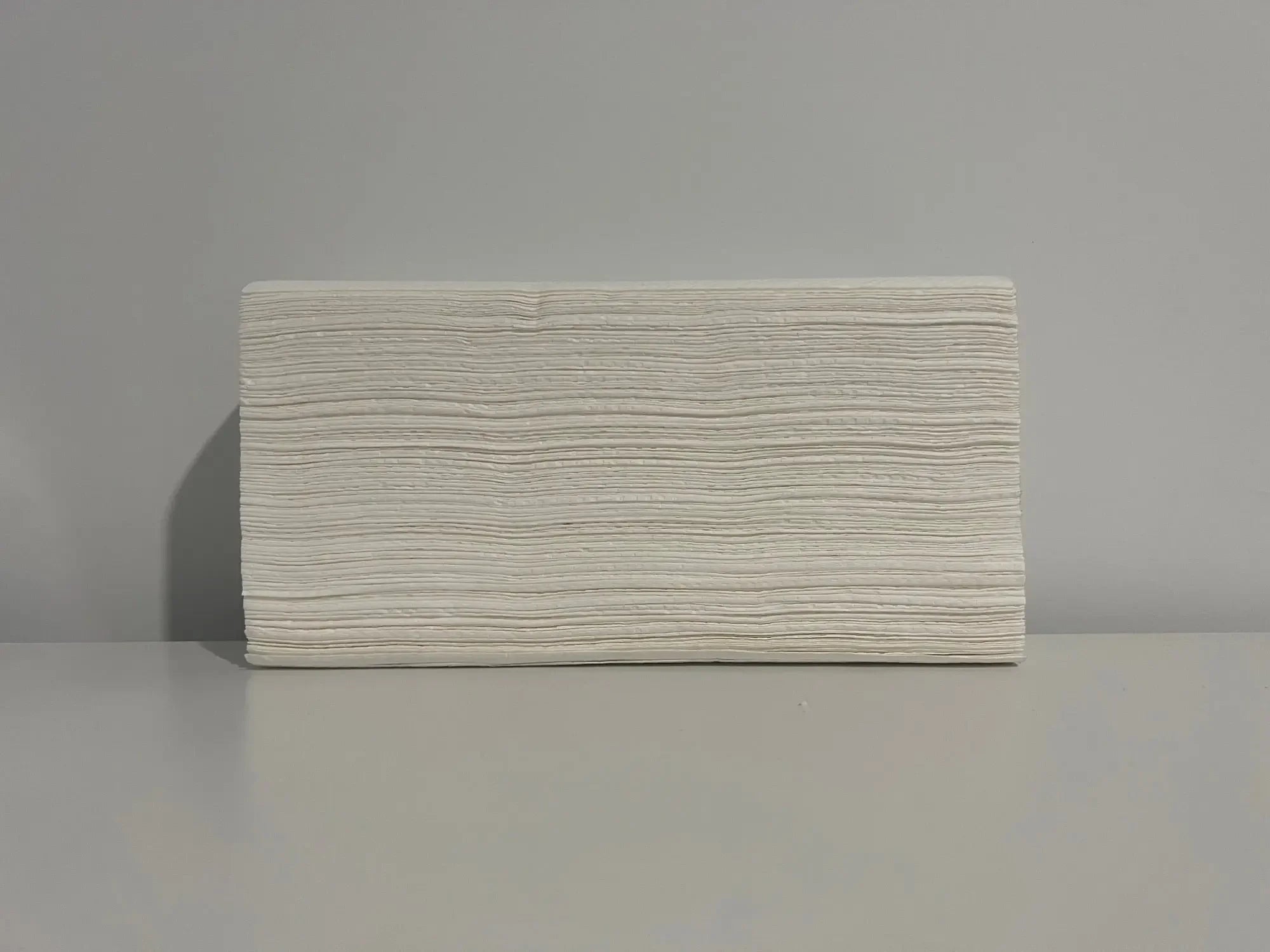 Stack of white disposable paper hand towels on a grey surface