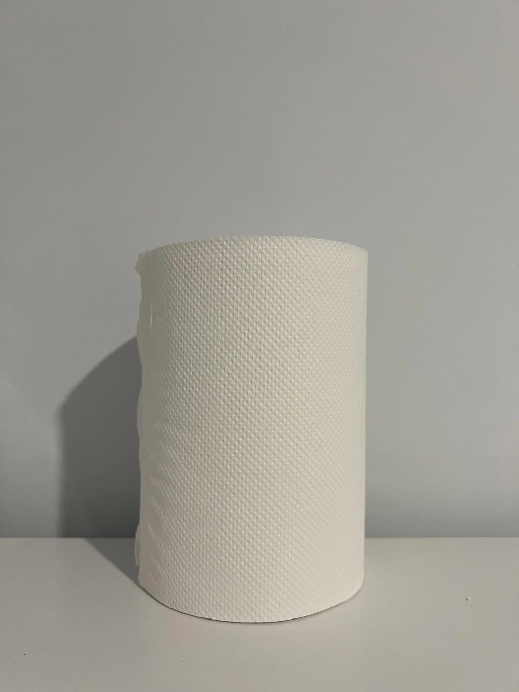 White textured paper towel roll on a plain surface for cleaning or kitchen use